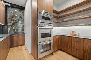Kitchen featuring modern cabinets, wood finish cabinets, double oven, and light wood finished floors