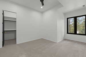 Unfurnished bedroom featuring light carpet, a walk in closet, a ceiling fan, and recessed lighting