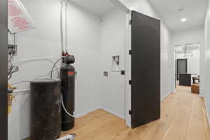 Laundry area featuring light wood-style flooring, washer hookup, and recessed lighting