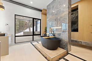 Full bath with vanity, a freestanding tub, and light tile patterned floors