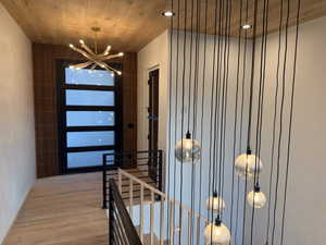 Entrance foyer with wooden ceiling, a chandelier, and wood finished floors