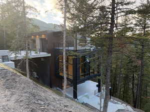 View of property exterior featuring a mountain view, a balcony, stucco siding, and a forest view