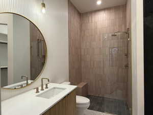 Full bathroom featuring vanity, tiled shower, and dark tile patterned floors