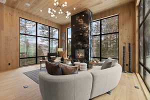 Living area featuring wooden walls, wood ceiling, light wood finished floors, a fireplace, and suspended lighting