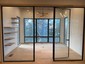 Office doorway with hardwood / wood-style floors and a chandelier