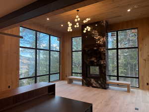 Living room featuring wooden walls, light wood-type flooring, wooden ceiling, recessed lighting, and a multi sided fireplace