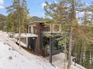 View of snow covered exterior with a patio, a mountain view, and a balcony