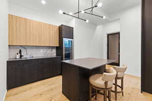 Kitchen featuring modern cabinets, a kitchen breakfast bar, light wood finished floors, and dark wood finish cabinets