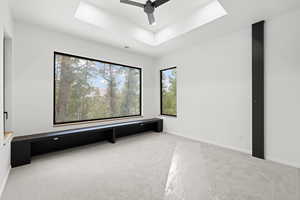 Home theater featuring a raised ceiling, light colored carpet, and a ceiling fan