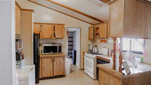 Kitchen with black appliances, vaulted ceiling, light countertops, a textured ceiling, and open shelves