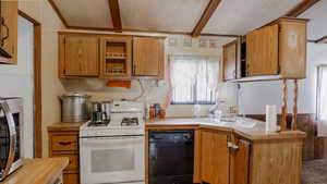 Kitchen with gas range gas stove, black dishwasher, stainless steel microwave, light countertops, and beam ceiling