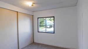 Unfurnished bedroom with carpet flooring, a textured ceiling, and a closet