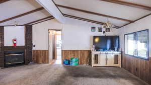 Unfurnished living room with carpet flooring, wood walls, wainscoting, a brick fireplace, and a chandelier