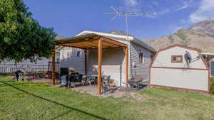 Back of house featuring a yard, a mountain view, a patio, and a storage shed
