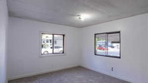 Carpeted spare room with a textured ceiling and baseboards