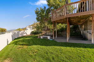Fenced backyard featuring a wooden deck and a patio