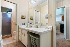Bathroom featuring a textured wall, a stall shower, vanity, and light tile patterned flooring