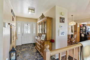 Entryway featuring a textured wall, a textured ceiling, and stone flooring