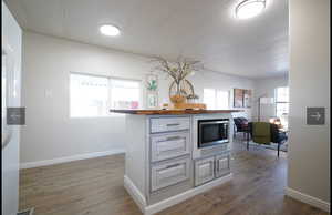 Kitchen with wooden counters, dark wood-style floors, stainless steel microwave, and freestanding refrigerator