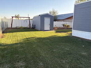 Fenced backyard featuring a storage unit