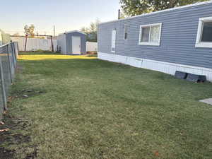 Fenced backyard featuring a storage unit