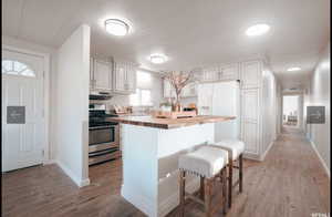 Kitchen with a breakfast bar area, butcher block countertops, stainless steel range with gas cooktop, a kitchen island, and light wood-style flooring