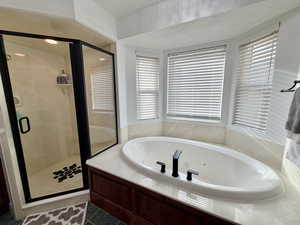 Bathroom with a jetted tub, a shower stall, tile patterned flooring, and a textured ceiling