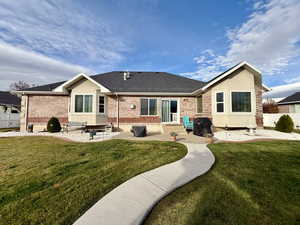 Back of house with brick siding, a patio area, and roof with shingles