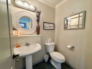 Bathroom with crown molding, dark tile patterned floors, and a textured ceiling