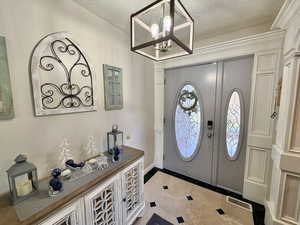 Foyer featuring a textured ceiling, a chandelier, and inlaid floor details