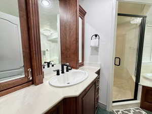 Full bathroom featuring vanity, a stall shower, and a textured ceiling