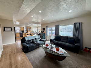 Living room featuring a textured ceiling, light wood finished floors, and recessed lighting