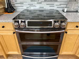 Kitchen view of double oven range, light stone countertops, and backsplash