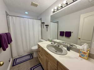 Full bathroom featuring vanity, light tile patterned floors, a textured ceiling, and a shower with curtain