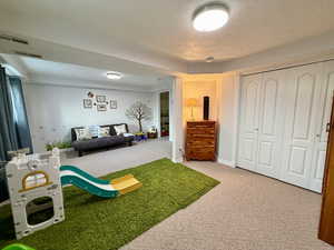 Recreation room featuring carpet flooring and a textured ceiling