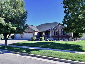 View of front of home featuring brick siding, concrete driveway, a front yard, an attached garage, and a shingled roof
