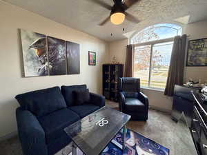 Carpeted living area with a textured ceiling and a ceiling fan