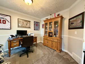 Office with a textured ceiling, ornamental molding, and light carpet
