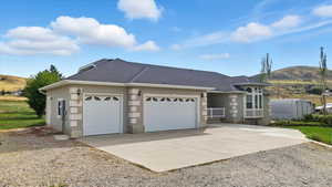 Ranch-style house featuring driveway, an attached garage, a shingled roof, and a mountain view