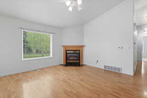 Lliving room featuring a fireplace with flush hearth, light wood-type flooring, ceiling fan