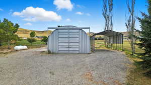 View of outbuilding with a detached carport, gravel driveway, and a mountain view
