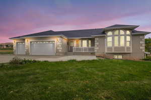 View of front facade featuring a garage, concrete driveway, a lawn, stucco siding, and covered porch