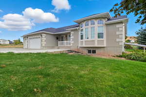 View of front of home with stucco siding, a front yard, concrete driveway, a garage, and roof with shingles