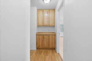 Bar area with light wood-type flooring, light brown cabinets, and light countertops