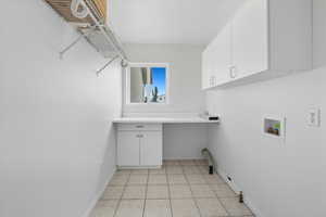 Washroom with light tile patterned floors, hookup for a washing machine, cabinet space, and gas dryer hookup