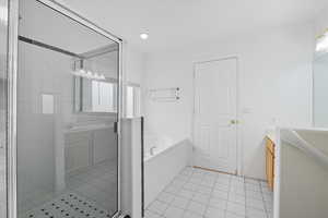 Bathroom featuring vanity, a garden tub, a stall shower, and light tile patterned flooring
