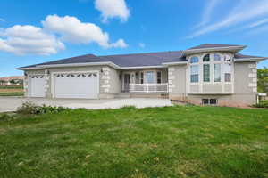 Home with a front yard, a garage, covered porch, driveway, and stucco siding