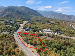 Aerial view of property and surrounding area featuring a mountainous background and property parcel outlined