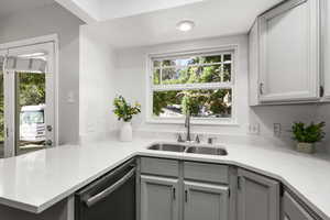 Kitchen featuring dishwasher, gray cabinets, and light stone countertops