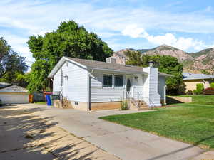 Single story home with a chimney, a mountain view, an outbuilding, and a front lawn